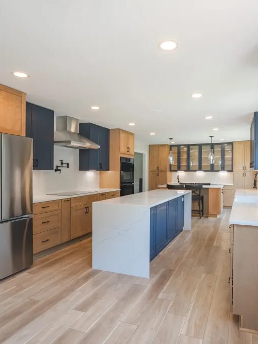 Transitional kitchen combining natural wood cabinetry with deep navy island and cabinets