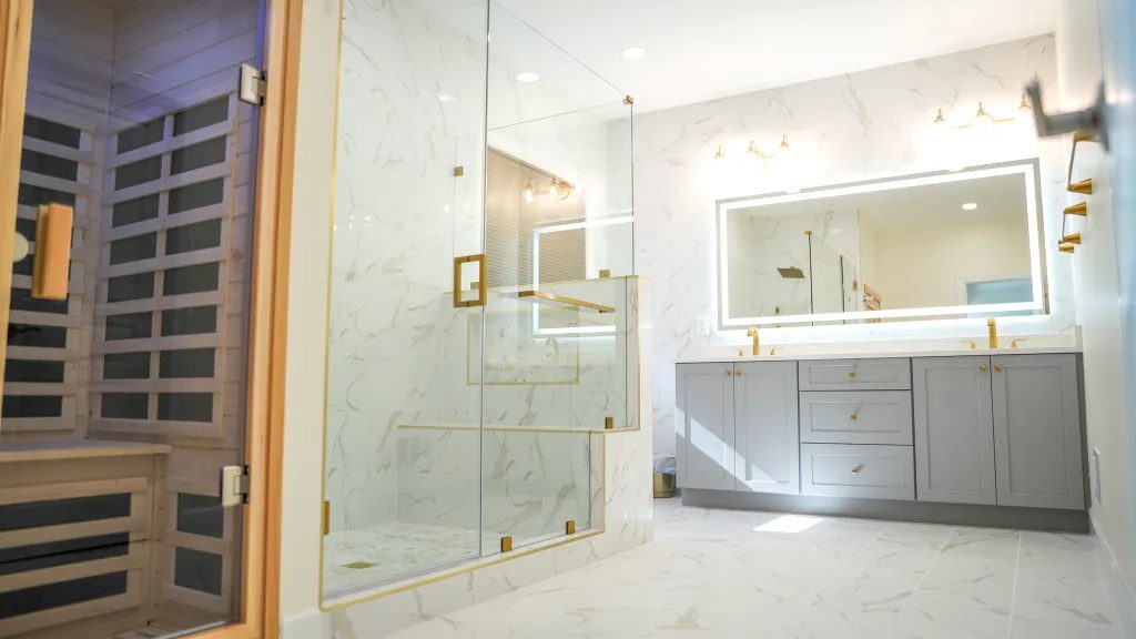 Spa style bathroom with marble walls, backlit mirror and a glass shower enclosure