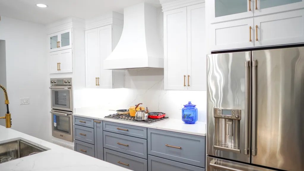 Kitchen with white uppers, blue grey base cabinets and a custom range hood