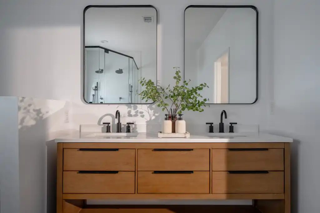 Bathroom with a warm wood double vanity and two rounded mirrors