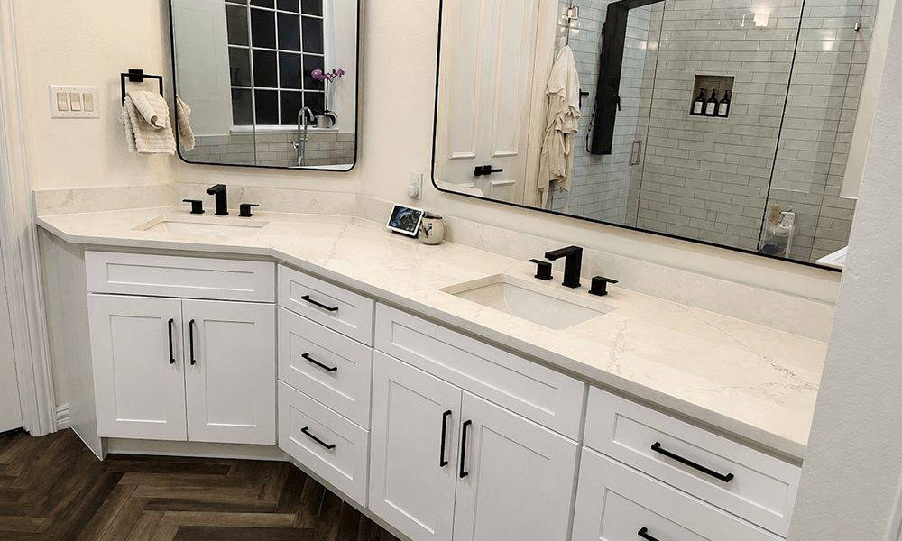 Bathroom with a corner double vanity over a herringbone wood floor